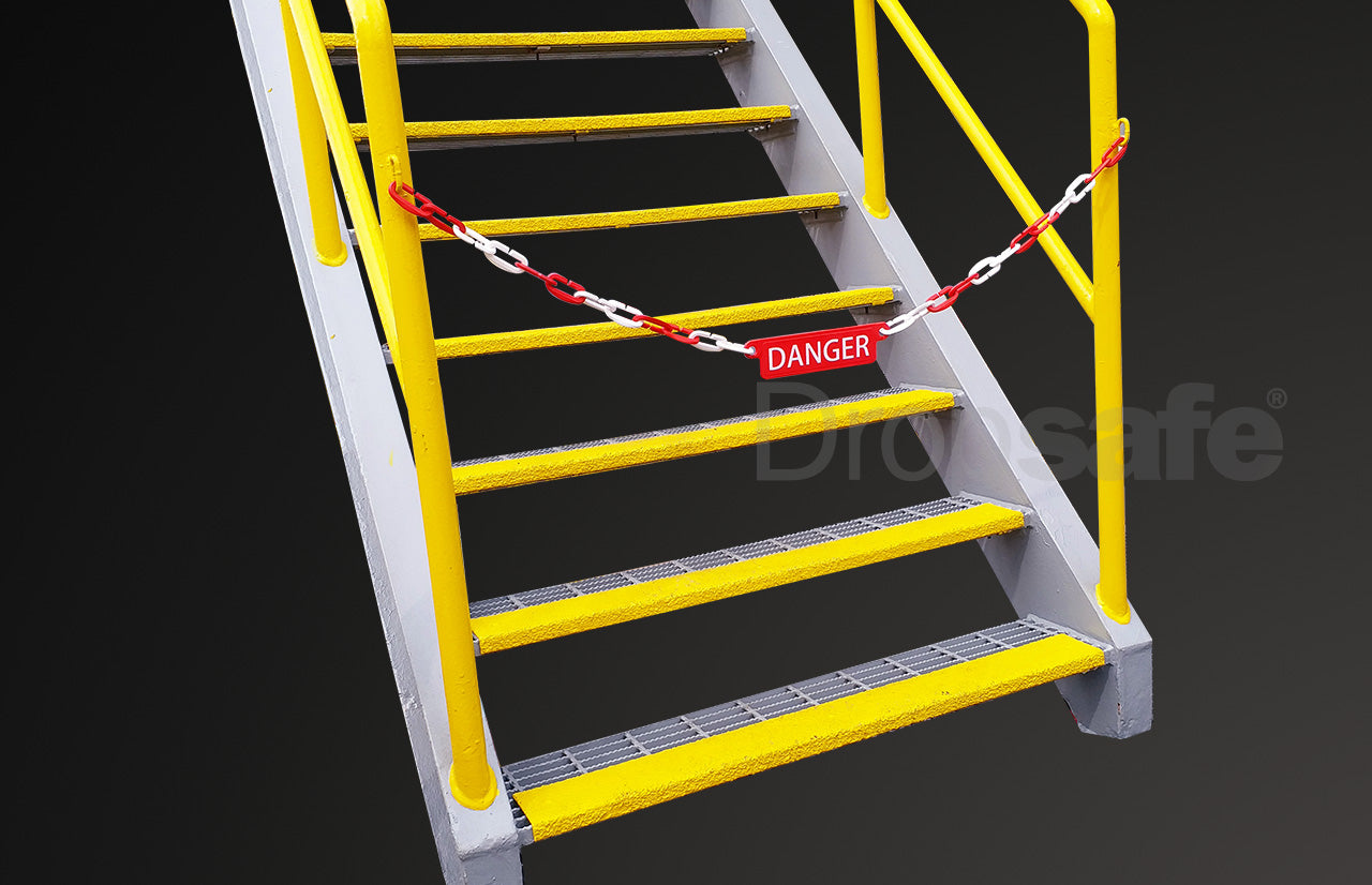 Red and white plastic chain link barricade, with DANGER sign, blocking the entry to a stairwell.