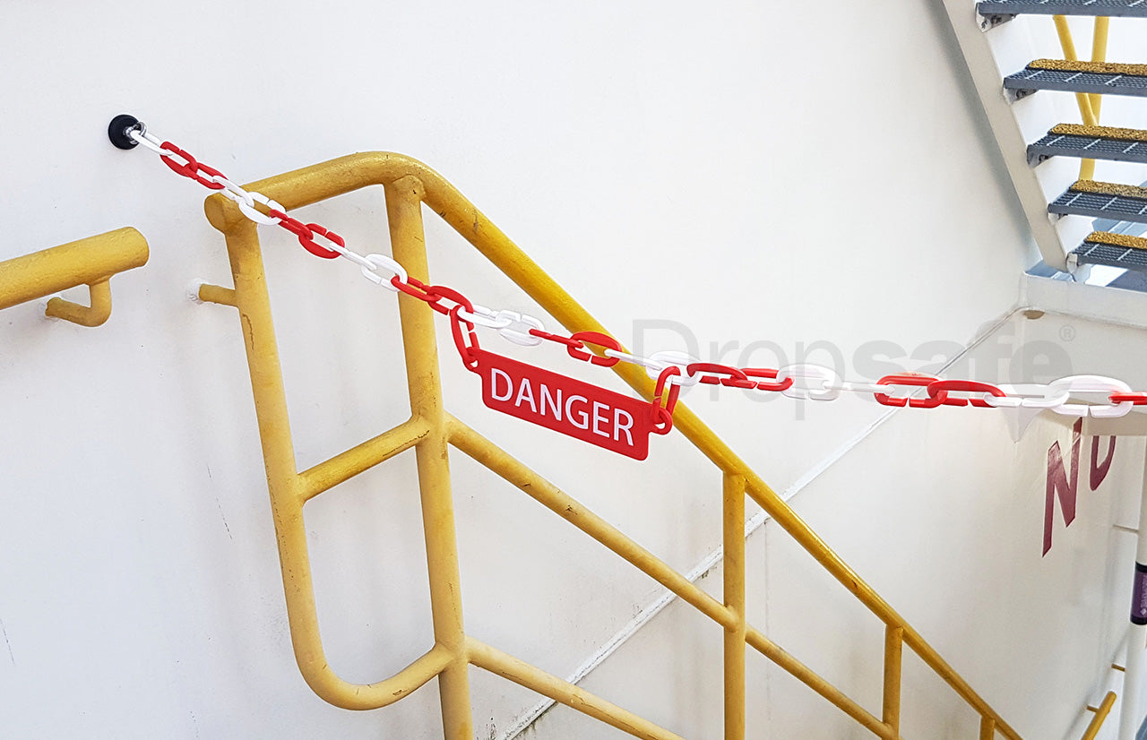 Red and white plastic chain link barricade, with DANGER sign, blocking the entry to a stairwell.