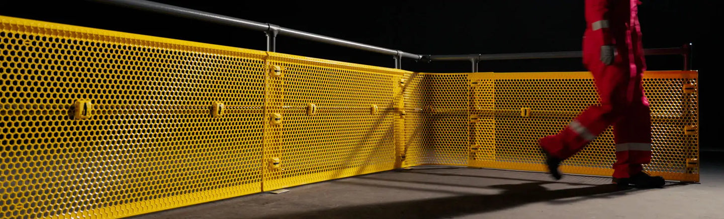 Bright yellow perforated metal safety barrier with a grid pattern and horizontal rails.