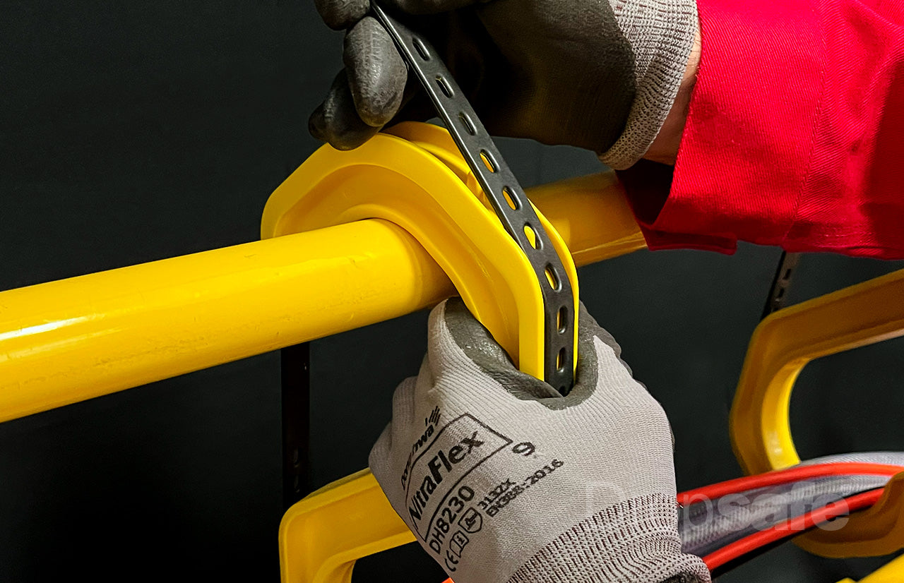 Gloved hands adjusting yellow plastic safety clamp with black metal strap on Cable Hook Medium