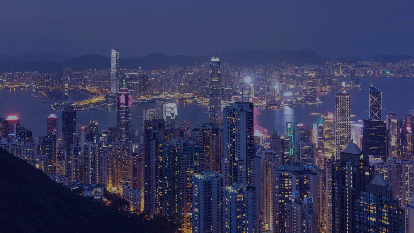 A dazzling nighttime cityscape of hong kong, featuring a dense cluster of illuminated skyscrapers with glowing windows and vibrant neon lights reflecting off the harbor waters.