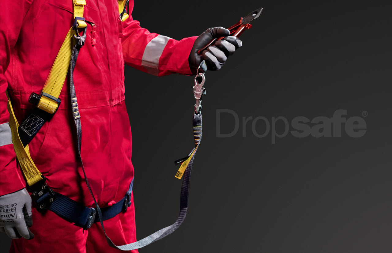 Worker in safety gear holds red-handled pliers on webbing tool lanyard