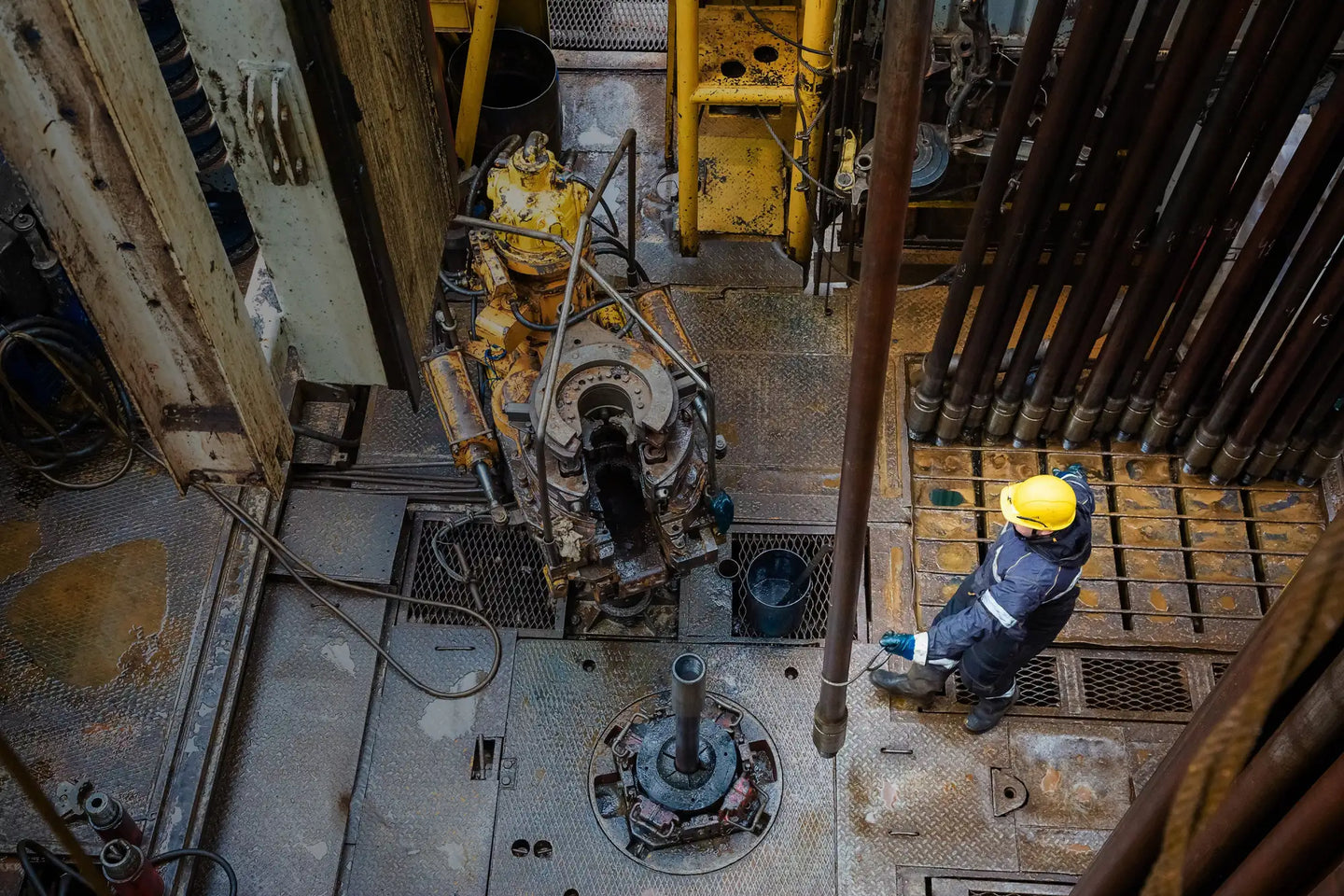 Yellow industrial drill rig with rusted metal components and hydraulic hoses