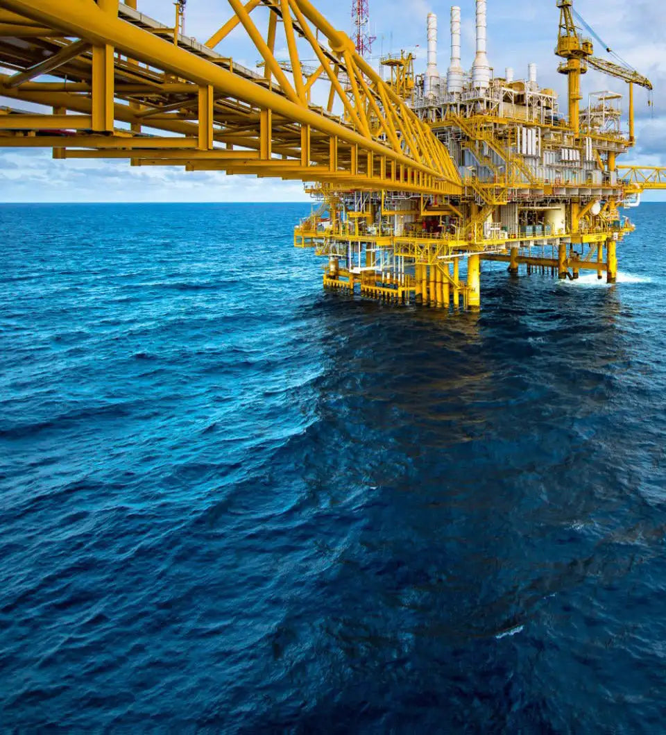 Yellow steel offshore oil platform with white cylindrical tanks and cranes